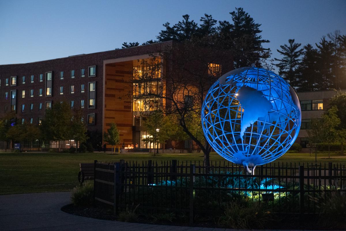 Campus globe at night with blue light shining on it.
