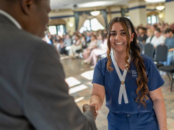 Nursing graduate Yirancis smiling during the Nursing Pinning Ceremony.