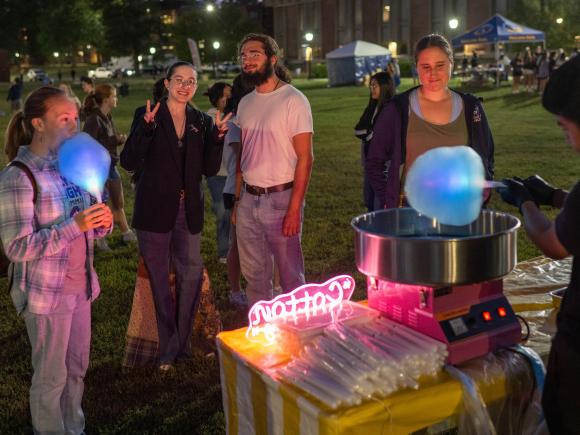 Students gather to get glowing cotton candy on the campus green