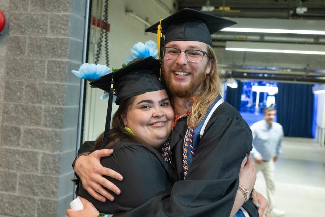 Two students smiling together at commencement ceremony.